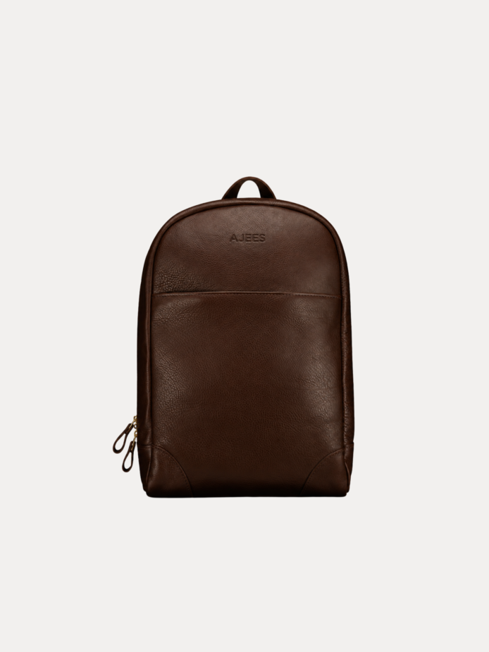 Image 1 (front view): Zenvik brown leather backpack with embossed AJEES logo, brass zippers and top carry handle