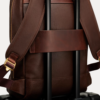Image 1 (front view): Zenvik brown leather backpack with embossed AJEES logo, brass zippers and top carry handle