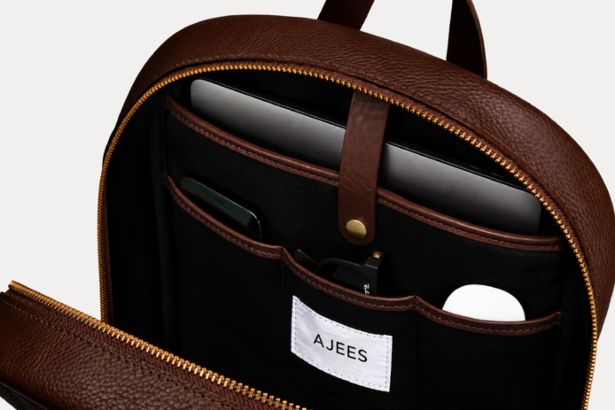Image 1 (front view): Zenvik brown leather backpack with embossed AJEES logo, brass zippers and top carry handle